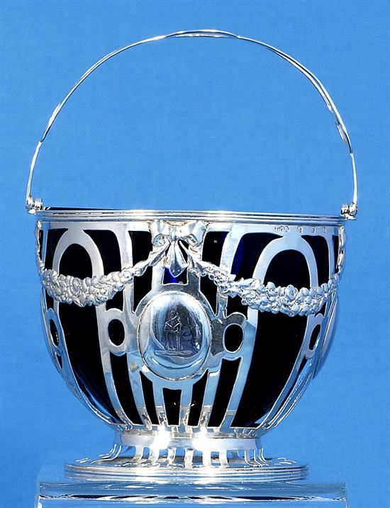 An Edwardian pierced silver sugar basket and blue glass liner, Height to handle 6”/155mm Dia 104mm Weight Silver only: 5.1oz/145grms